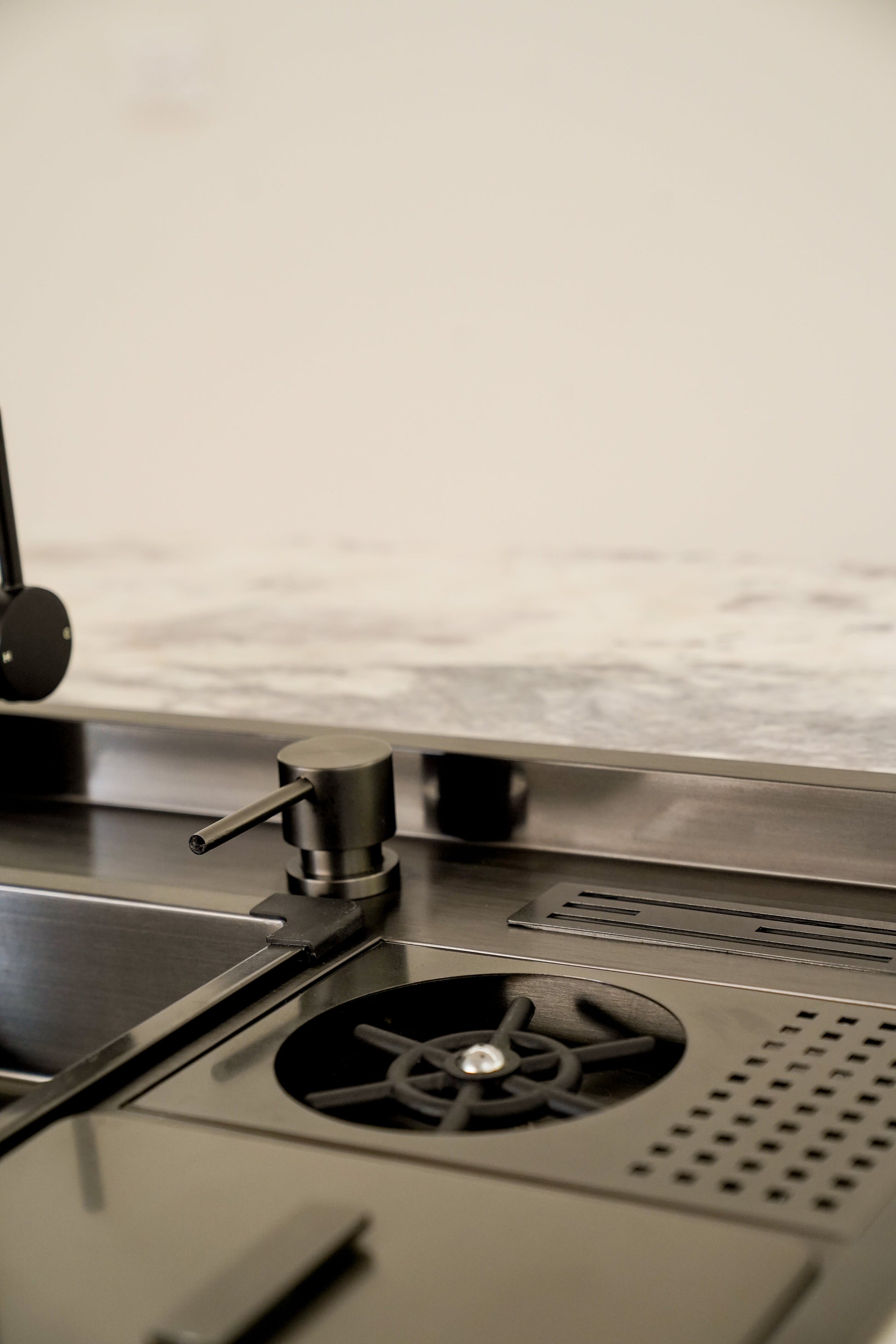 Elegantly designed ALIA Smart Sink displayed in a sophisticated kitchen, highlighting the integrated soap dispenser, high-pressure cup washer, compact waste bin, and knife rack with drain.